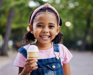 A young girls smiles with a half-eaten ice cream cone.
