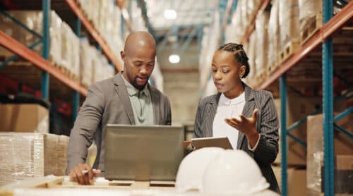 Collaboration, planning and people with laptop, factory or quality control for distribution with tech. Warehouse, teamwork and engineer with checklist for goods, logistics and discussion for shipping