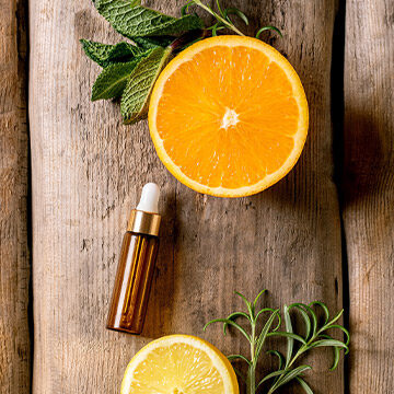 A sliced orange and brown essential oil cannister on a wooden table.