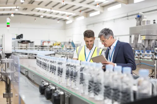 A foreman and lineworker inspect a production line.