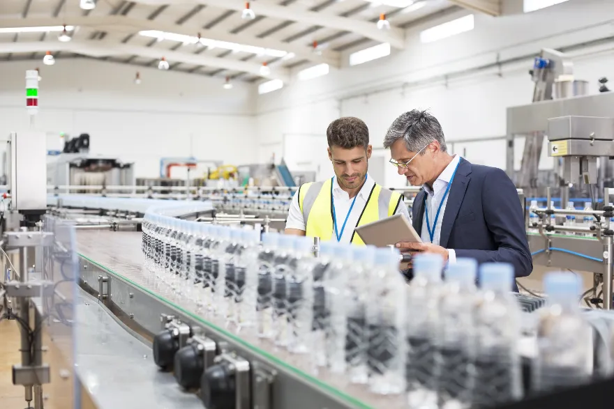 Two workers examine a production line up close.