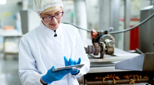 A food industry worker inspects product quality on the line.