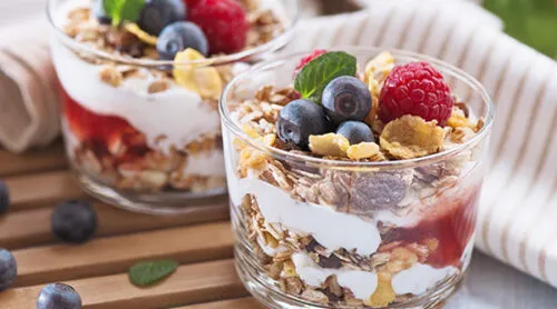 Two yogurt parfaits in glass cups sit on countertop.