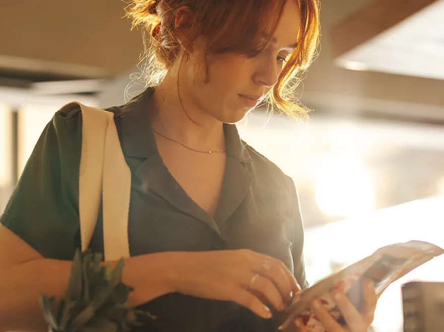 A woman inspects a food label in a grocery store.
