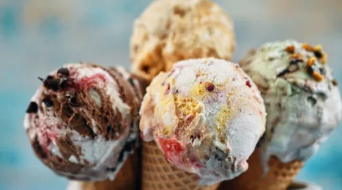 Four ice cream cones resting in a cup.