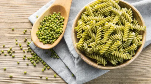 Pesto pasta sits prepared in a wooden bowl.