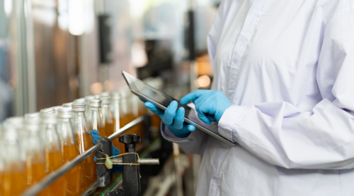 A worker monitors quality in a food and beverage manufacturing facility.