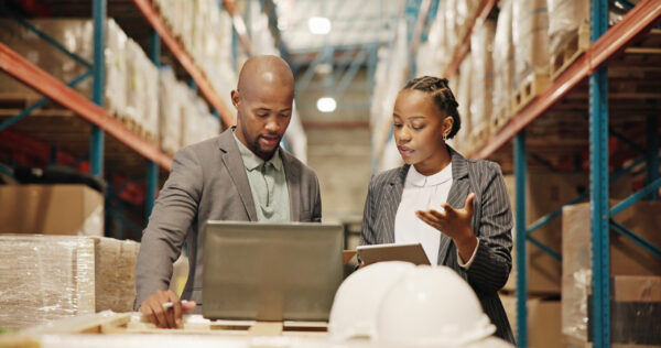 Collaboration, planning and people with laptop, factory or quality control for distribution with tech. Warehouse, teamwork and engineer with checklist for goods, logistics and discussion for shipping
