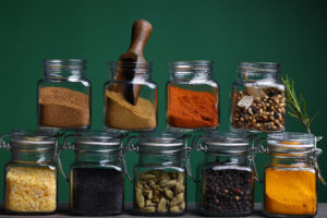 Glass jars of brightly covered spices on a shelf.